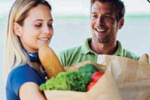 man and woman with grocery bags smiling